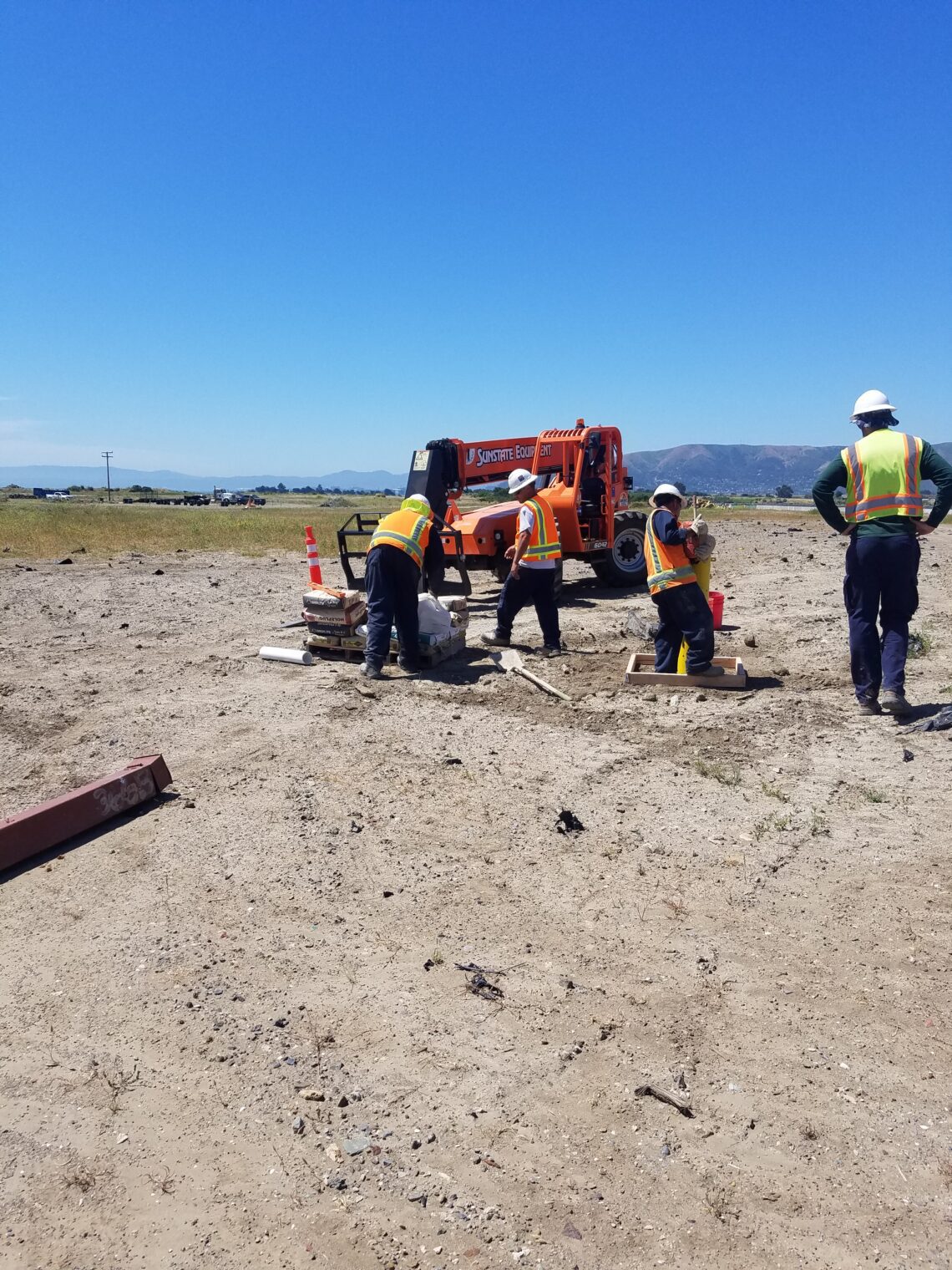 four people working in a sandy area