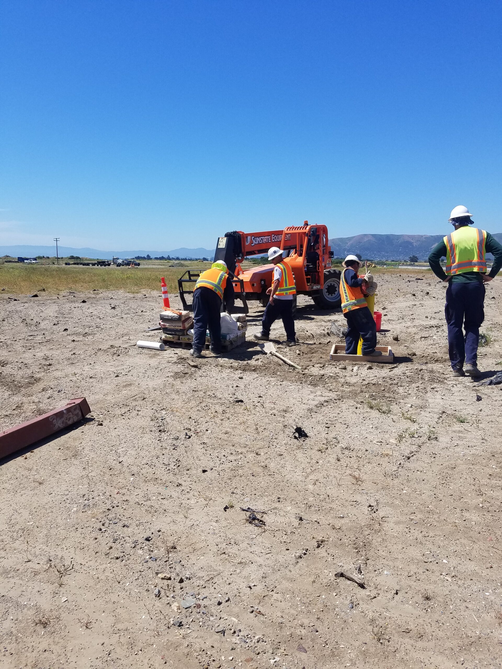 four people working in a sandy area