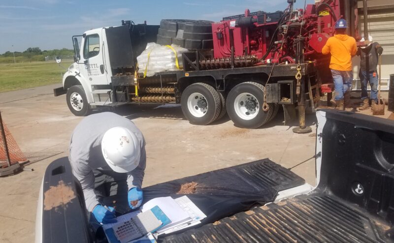 20190725_104653 person looking at dirt while writing and equipment in background