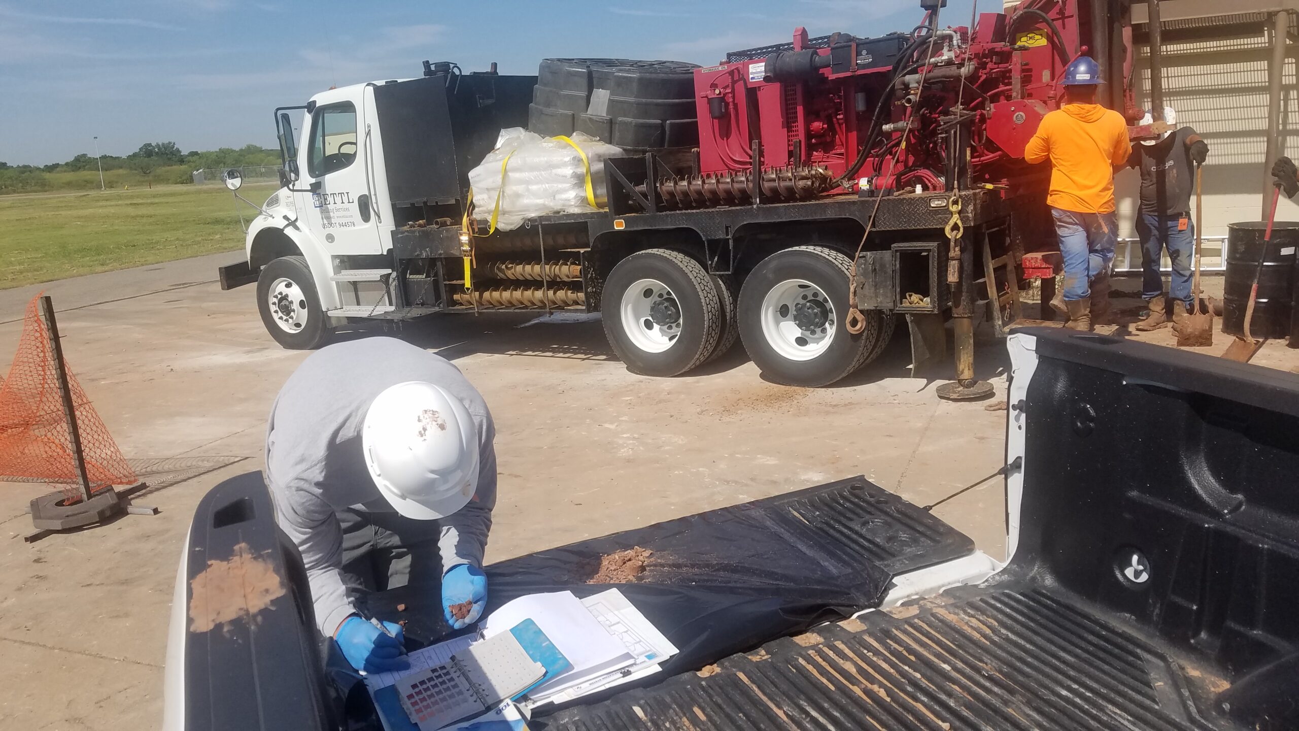 person looking at dirt while writing and equipment in background