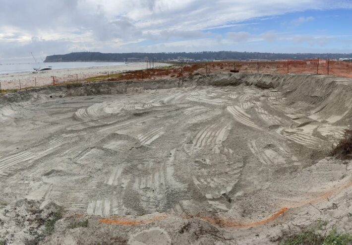 large sand hole dug near water