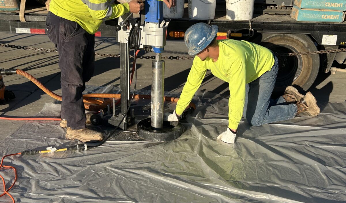 Concrete Cutting person holding concrete cutting equipment and person on knees helping