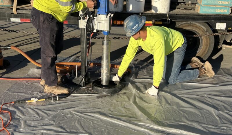 Concrete Cutting person holding concrete cutting equipment and person on knees helping