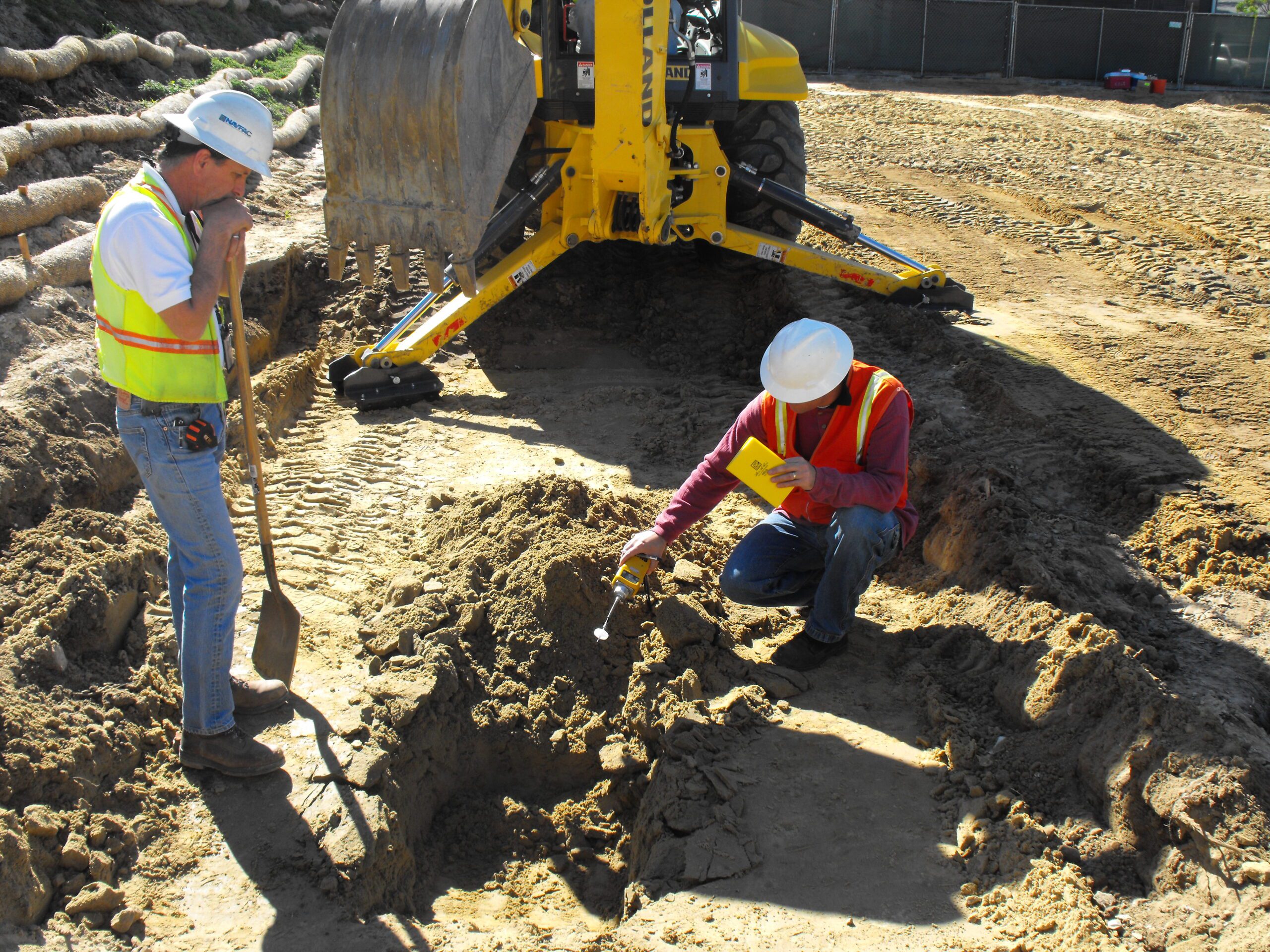 Harrier_Yuma_DSCF0029 person measuring and another person resting on a shovel with and excavator in background