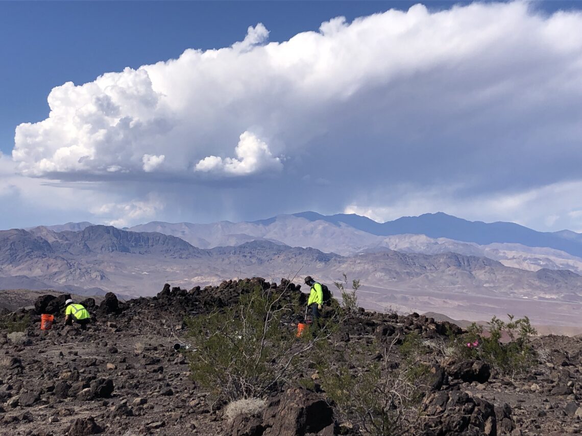 people picking up rubble in rocky mountainous area