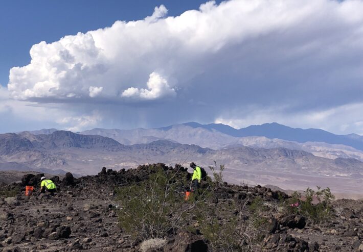 people picking up rubble in rocky mountainous area