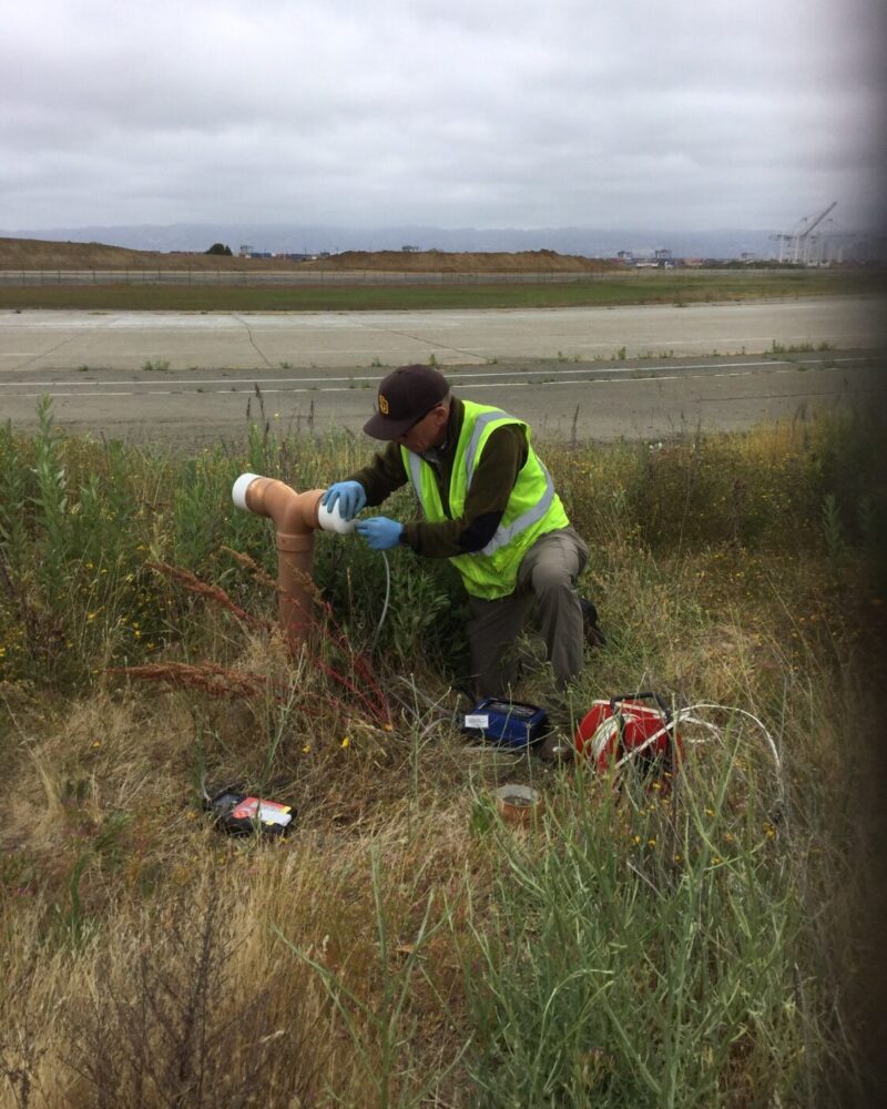 Landfill Gas Measurement person working in grassy area on tubing