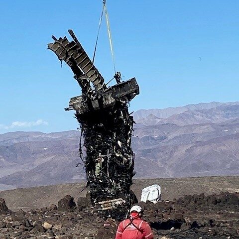 Lift rubble being pulled up into the air with person in the red nearby