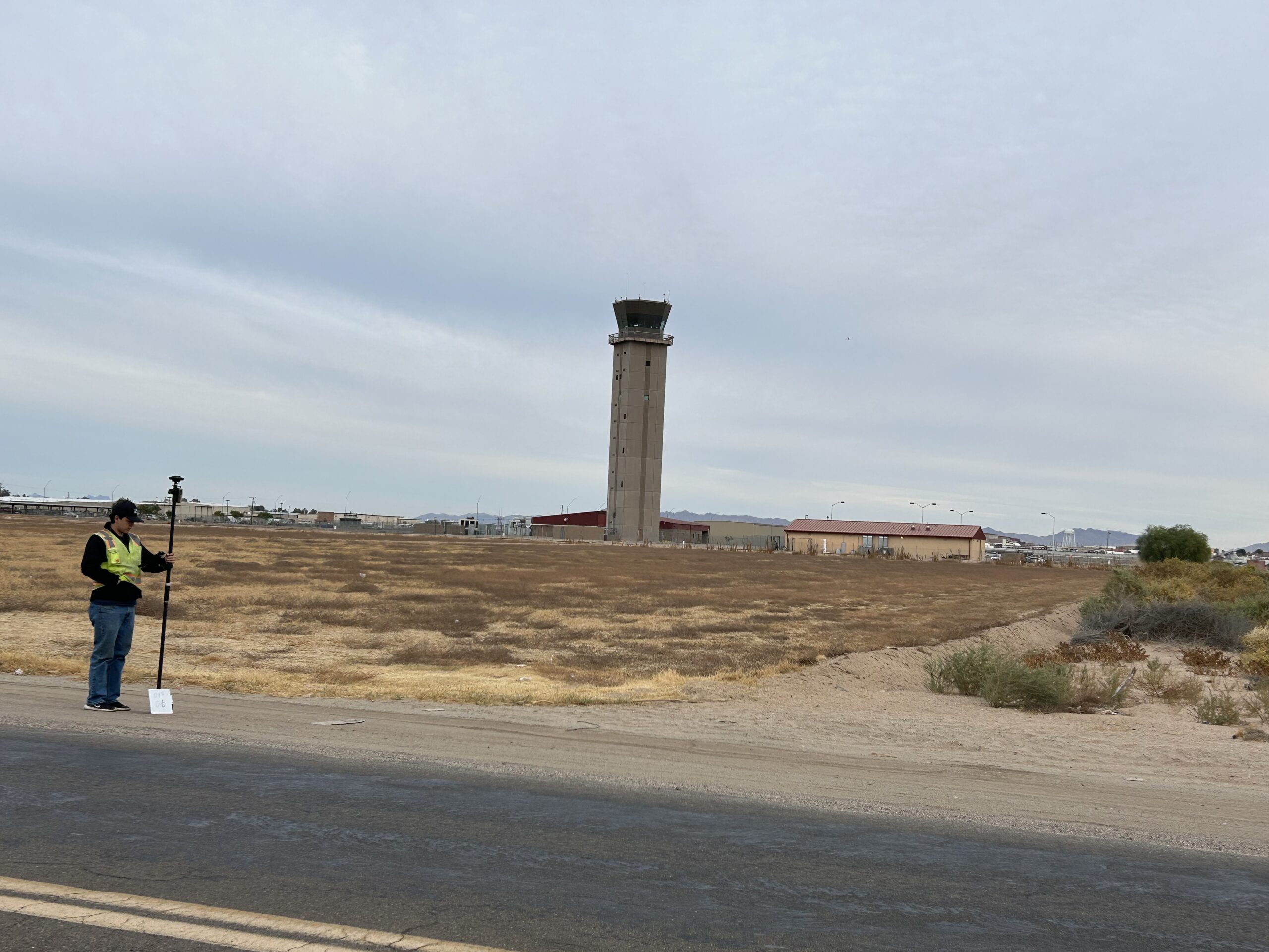 person holding measuring tool in front of air traffic control tower
