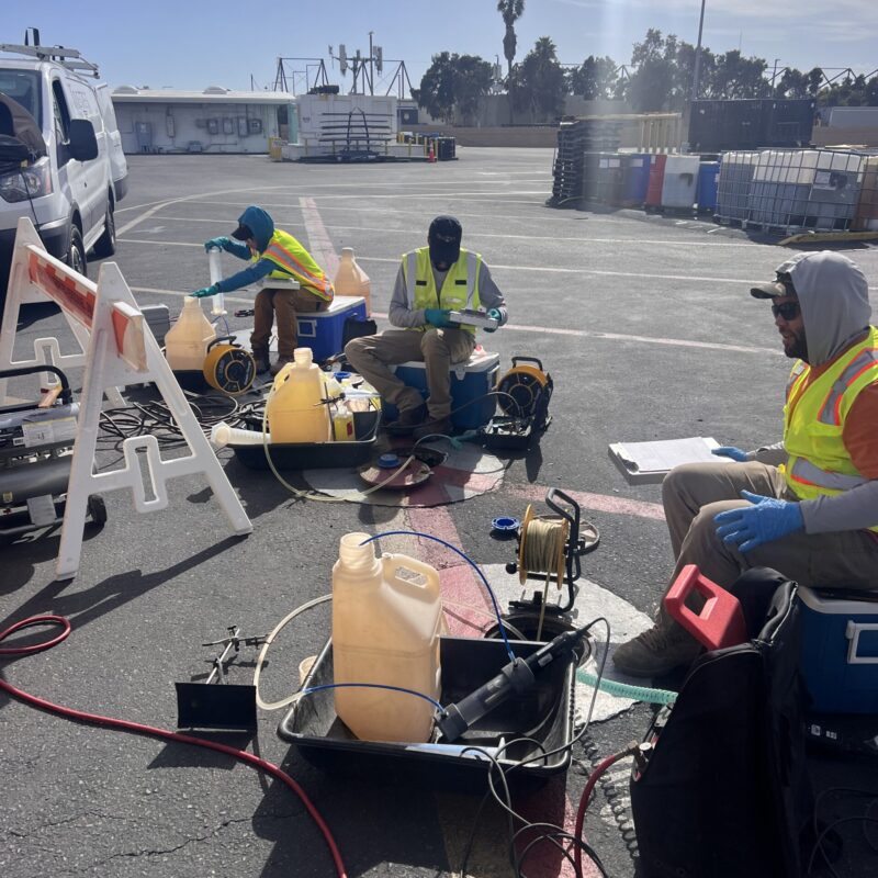 OU11gwsampling people sitting around equipment working in a parking lot