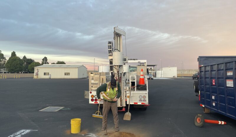 OU11handauger person hand drilling in the parking lot by equipment truck
