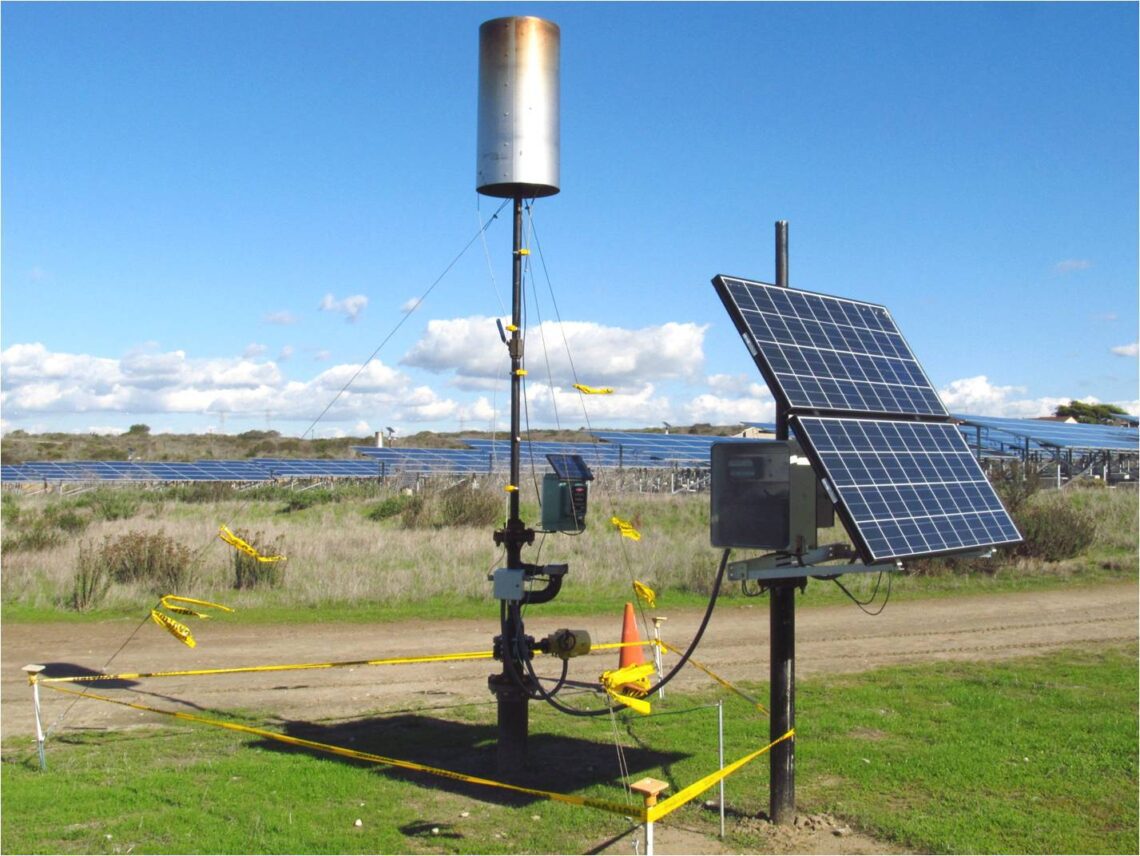 small solar panel and tall equipment with large solar field behind