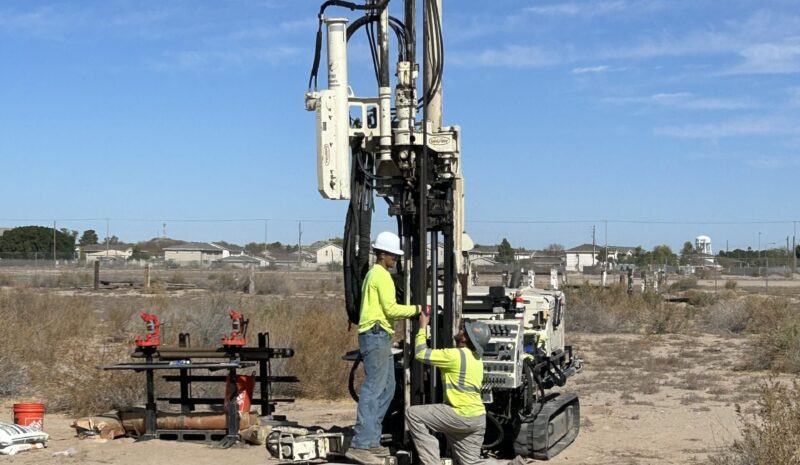 Site 9 DP sampling two people using drilling equipment in brush area