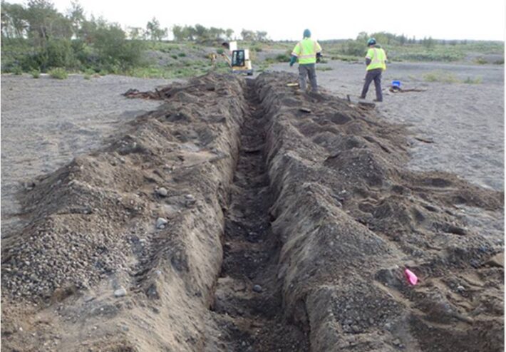 two people near large dirt trench that was dug up
