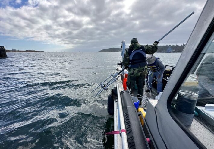 person holding a trident equipment on a boat