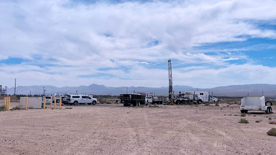 large sand dirt area with work truck and mountains on the far horizon
